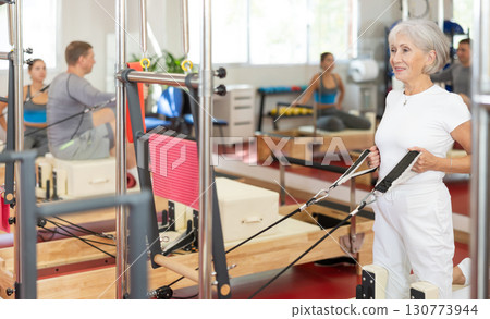 Elderly woman training her arms using straps 130773944