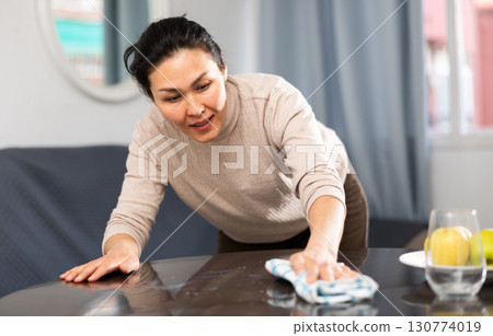 Asian woman wipes the table with a rag Asian woman wipes the table with a rag 130774019