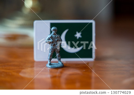 A tin soldier on the background of the flag of Pakistan. India Pakistan military conflict 130774029