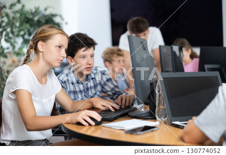 Boy and girl learning to work on computer in classroom Boy and girl learning to work on computer in classroom 130774052