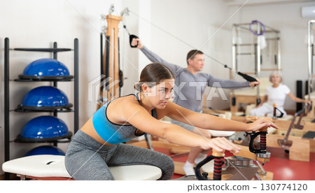 Young girl during Pilates training performs exercises and tasks on heron pulley tower 130774120