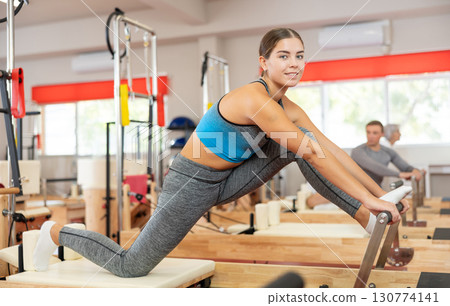 Girl performs exercise on reformer to improve coordination, balance, and posture Girl performs exercise on reformer to improve coordination, balance, and posture 130774141