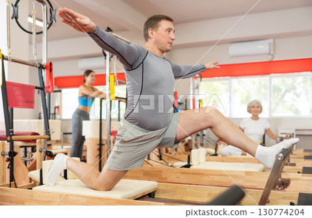 Adult man doing stretching on pilates machine 130774204