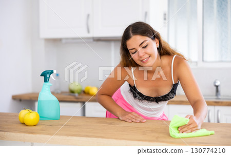 Smiling housewife using rag to wash table 130774210