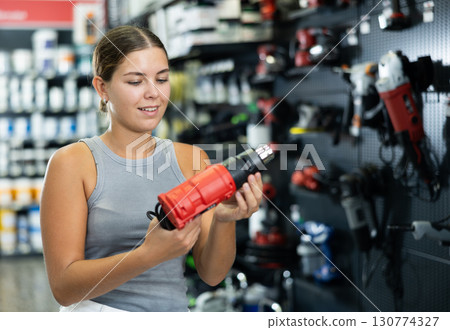 Woman buys electric drill, collect necessary supplies in store according to list for apartment repairs 130774327