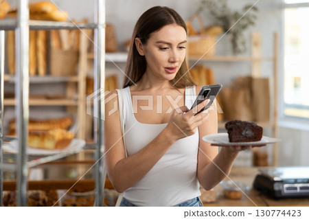 Young girl scanning pastry on paper plate in bakery 130774423
