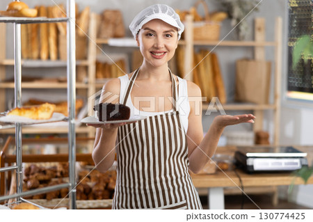 Young saleswoman holding piece of pastry in paper plate Young saleswoman holding piece of pastry in paper plate 130774425