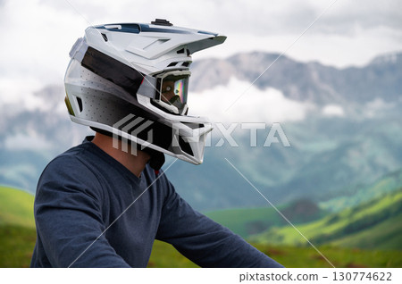 Portrait of mountain biker riding down the mountain. Close up of cyclist on hill against beautiful colorful sky and clouds. Mountain biker cycling in summer inspiring mountain landscape Portrait of mountain biker riding down the mountain. Close up of cyclist on hill against beautiful colorful sky and clouds. Mountain biker cycling in summer inspiring mountain landscape 130774622