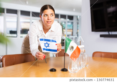 Employee of delegation prepares negotiating table - sets up flag of Mexico and Greece 130774631