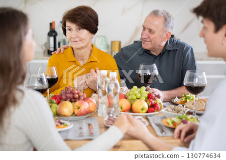 Father and mother together with adult children talking at dinner table at home Father and mother together with adult children talking at dinner table at home 130774634