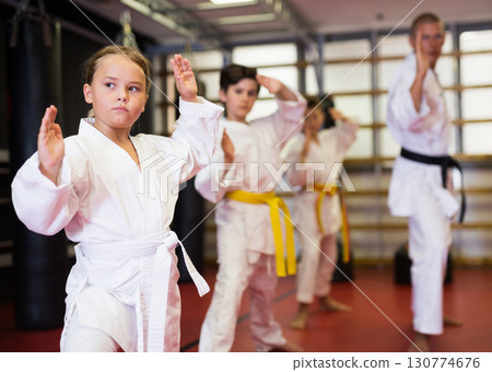 Girl practicing new moves during karate class Girl practicing new moves during karate class 130774676