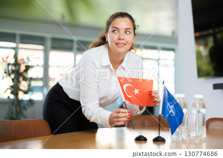 Employee of delegation prepares negotiating table - sets up flag of NATO and Turkey Employee of delegation prepares negotiating table - sets up flag of NATO and Turkey 130774686
