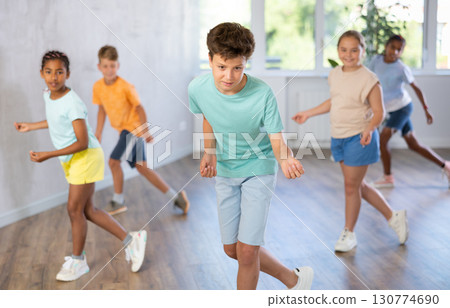 Cheerful tween boy dancing with group of children in choreography class Cheerful tween boy dancing with group of children in choreography class 130774690