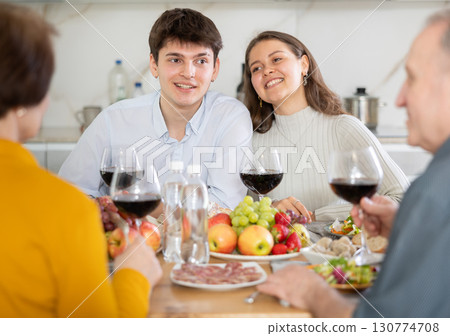 Young girl and guy enjoying festive dinner with elderly parents Young girl and guy enjoying festive dinner with elderly parents 130774708