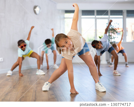 Girl performs choreographic exercises and teaches energetic mobile social dance hip hop with friends 130774717