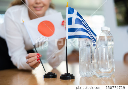Young female secretary preparing room for international negotiations between greece and japan 130774719