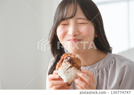 A young woman eating a muffin with relish 130774747