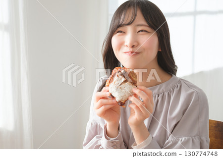 A young woman eating a muffin with relish 130774748