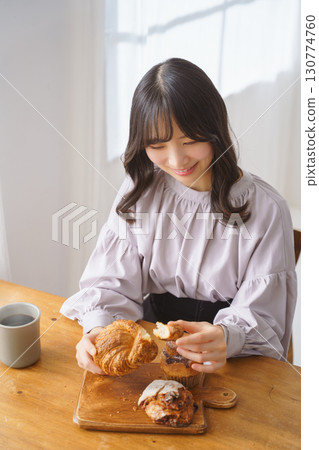 A young woman eating a muffin with relish 130774760