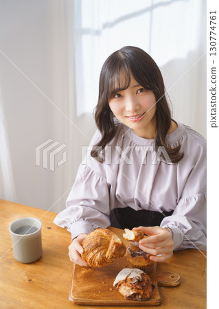 A young woman eating a muffin with relish 130774761