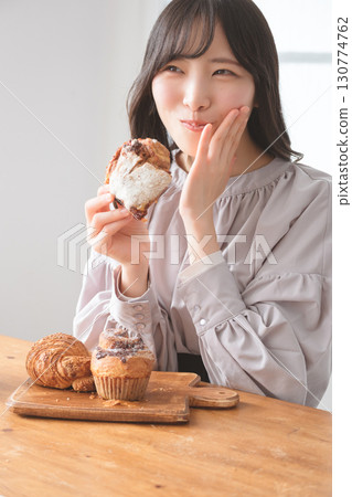 A young woman eating a muffin with relish 130774762