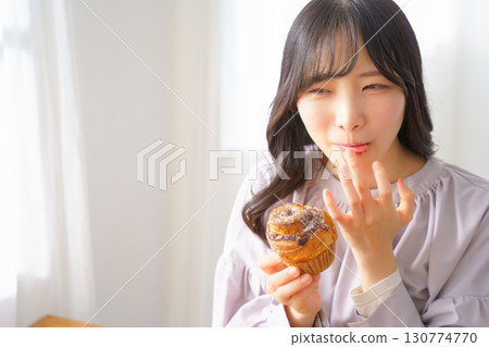 A young woman eating a muffin with relish 130774770