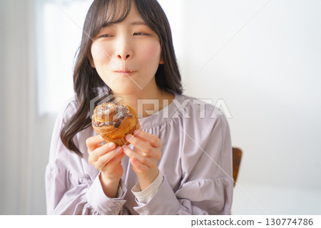 A young woman eating a muffin with relish 130774786