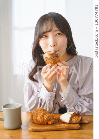 A young woman eating a muffin with relish 130774793