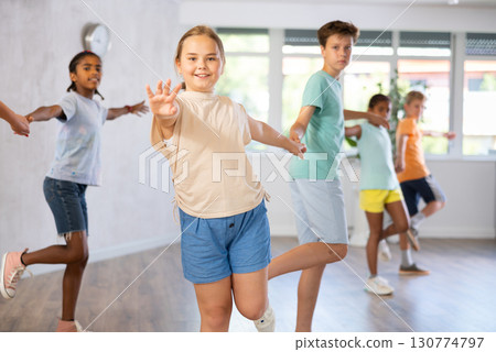 Smiling tween girl practicing vigorous dance in pair with boy Smiling tween girl practicing vigorous dance in pair with boy 130774797