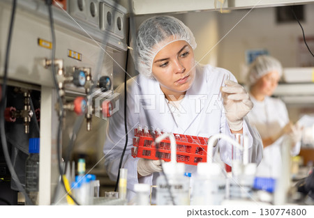 Female scientist researcher looking at reaction in test tube while performing biochemical tests in lab 130774800