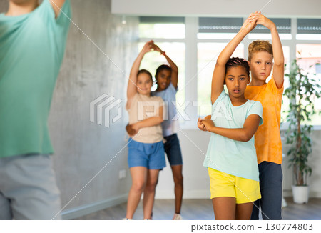 Light-skinned boy and African girlie learn figures of pair jive dance and train before competition 130774803