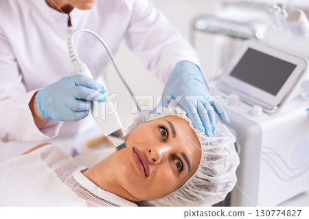 Young woman undergoing facial skin cleansing with ultrasonic shovel Young woman undergoing facial skin cleansing with ultrasonic shovel 130774827