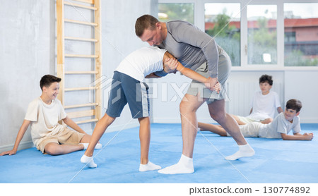 Skilled trainer demonstrating self-defense technique on juvenile practitioner Skilled trainer demonstrating self-defense technique on juvenile practitioner 130774892