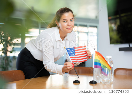 Young lady sets miniatures flags of LGBT and USA before international negotiations 130774893