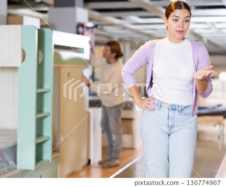 Happy woman choosing kids furniture in furniture showroom Happy woman choosing kids furniture in furniture showroom 130774907