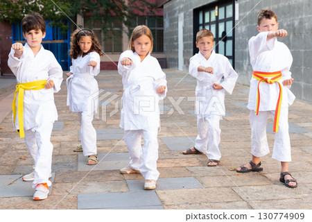 Tween girls and boys practicing taekwondo during outdoors group class 130774909