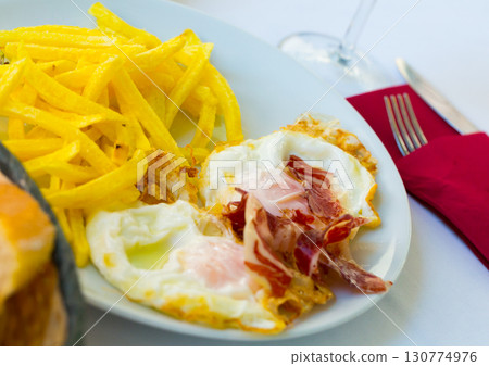 Fried eggs with Iberico ham and potatoes Fried eggs with Iberico ham and potatoes 130774976