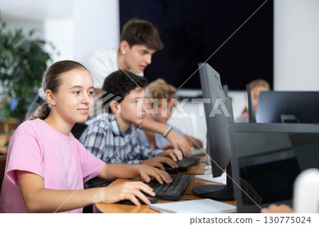 Preteen girl working with computer programs in training room 130775024