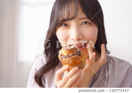 A young woman eating a muffin with relish A young woman eating a muffin with relish 130775437
