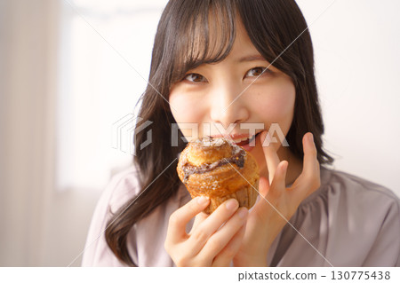 A young woman eating a muffin with relish A young woman eating a muffin with relish 130775438