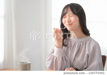 Young woman eating delicious cake 130775443