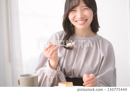Young woman eating delicious cake 130775449