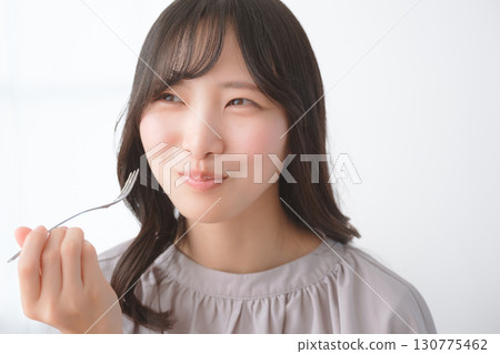 Young woman eating delicious cake 130775462