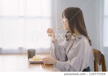 Young woman eating delicious cake 130775504