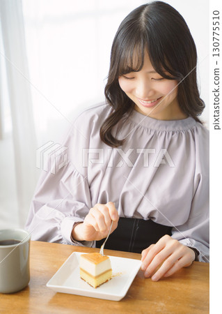 Young woman eating delicious cake 130775510