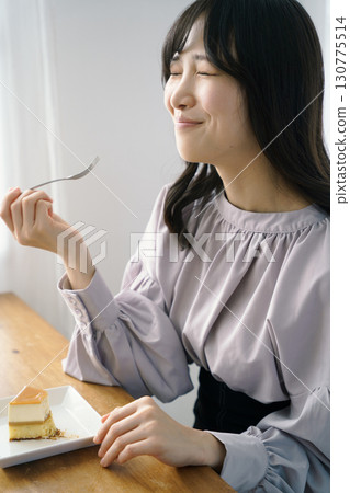 Young woman eating delicious cake 130775514