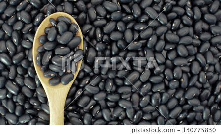 Raw black beans on wooden spoon placed over heap of black beans background. Perfect for illustrating legumes Raw black beans on wooden spoon placed over heap of black beans background. Perfect for illustrating legumes 130775830