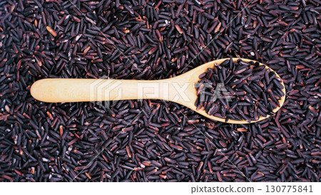 Close-up of riceberry rice grains in a wooden spoon with rice spread across the background, symbolizing organic food, nutrition, and healthy eating Close-up of riceberry rice grains in a wooden spoon with rice spread across the background, symbolizing organic food, nutrition, and healthy eating 130775841