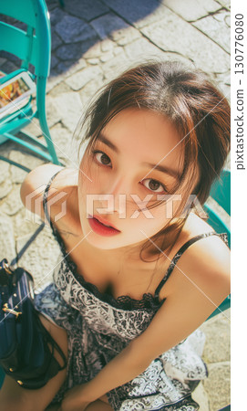 Young woman sitting outdoors in a stylish outfit with a captivating gaze on a sunny day in Korea 130776080
