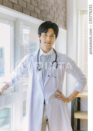 A young doctor in a white coat standing by the window A young doctor in a white coat standing by the window 130776281